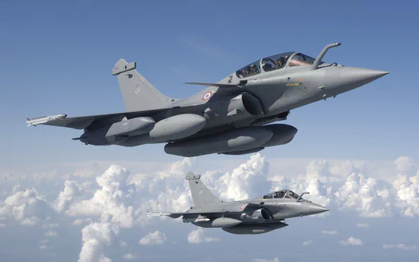 Two Dassault Rafale jet fighter warplanes fly in formation above clouds against a clear blue sky in this HD military aircraft desktop wallpaper.