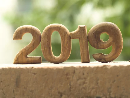 Holiday New Year 2019 wooden numbers on a ledge with green bokeh — 4K Ultra HD PC desktop wallpaper.