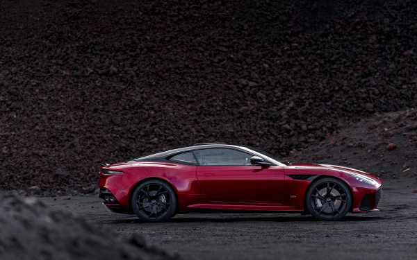Aston Martin DBS Superleggera supercar in deep red, showcased against a dark, rugged background as an HD PC desktop wallpaper.