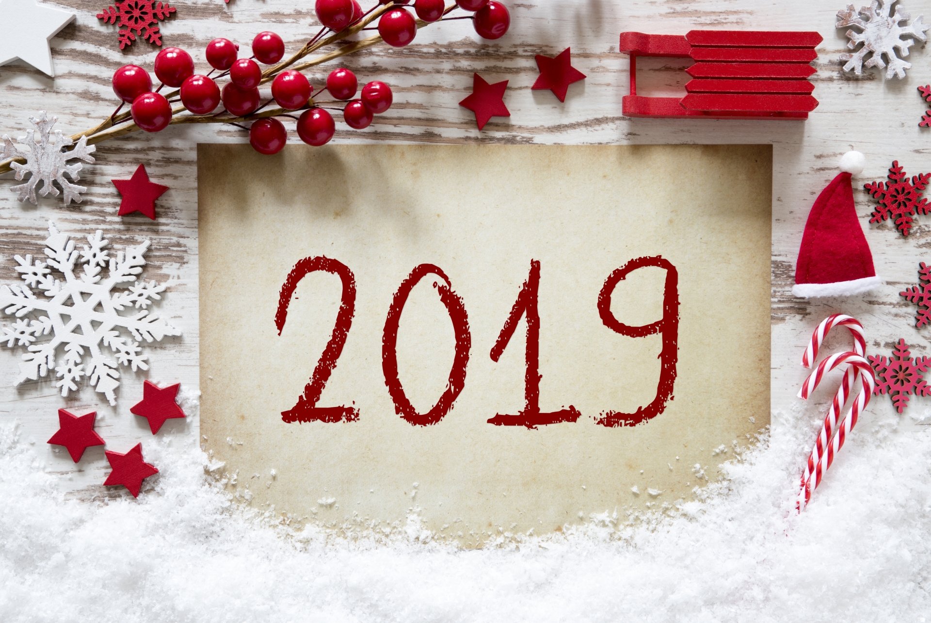 Holiday New Year 2019 5K Ultra HD PC desktop wallpaper and background: red 2019 on parchment surrounded by snow, red berries, stars, snowflakes, candy canes and a tiny Santa hat.
