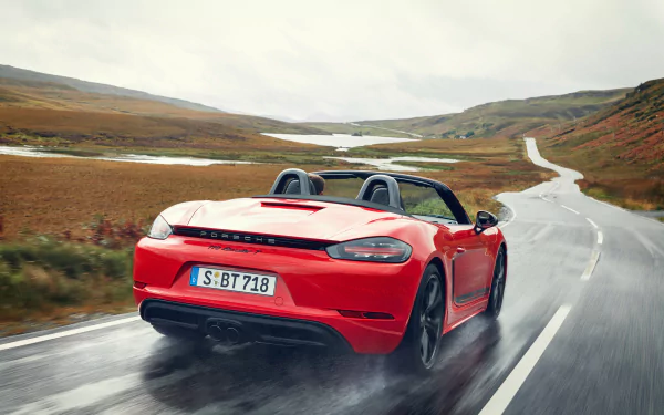 A red Porsche 718 Boxster GTS driving on a winding road through a scenic, open landscape, captured in a 4K Ultra HD desktop wallpaper.