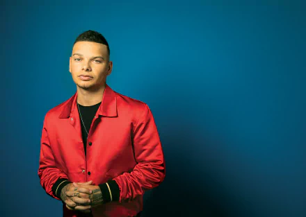 HD desktop wallpaper featuring a man in a red jacket against a blue background, tagged with Kane Brown.
