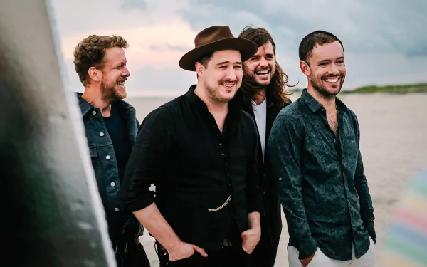 HD desktop wallpaper featuring the band Mumford & Sons casually posing with a beach backdrop.