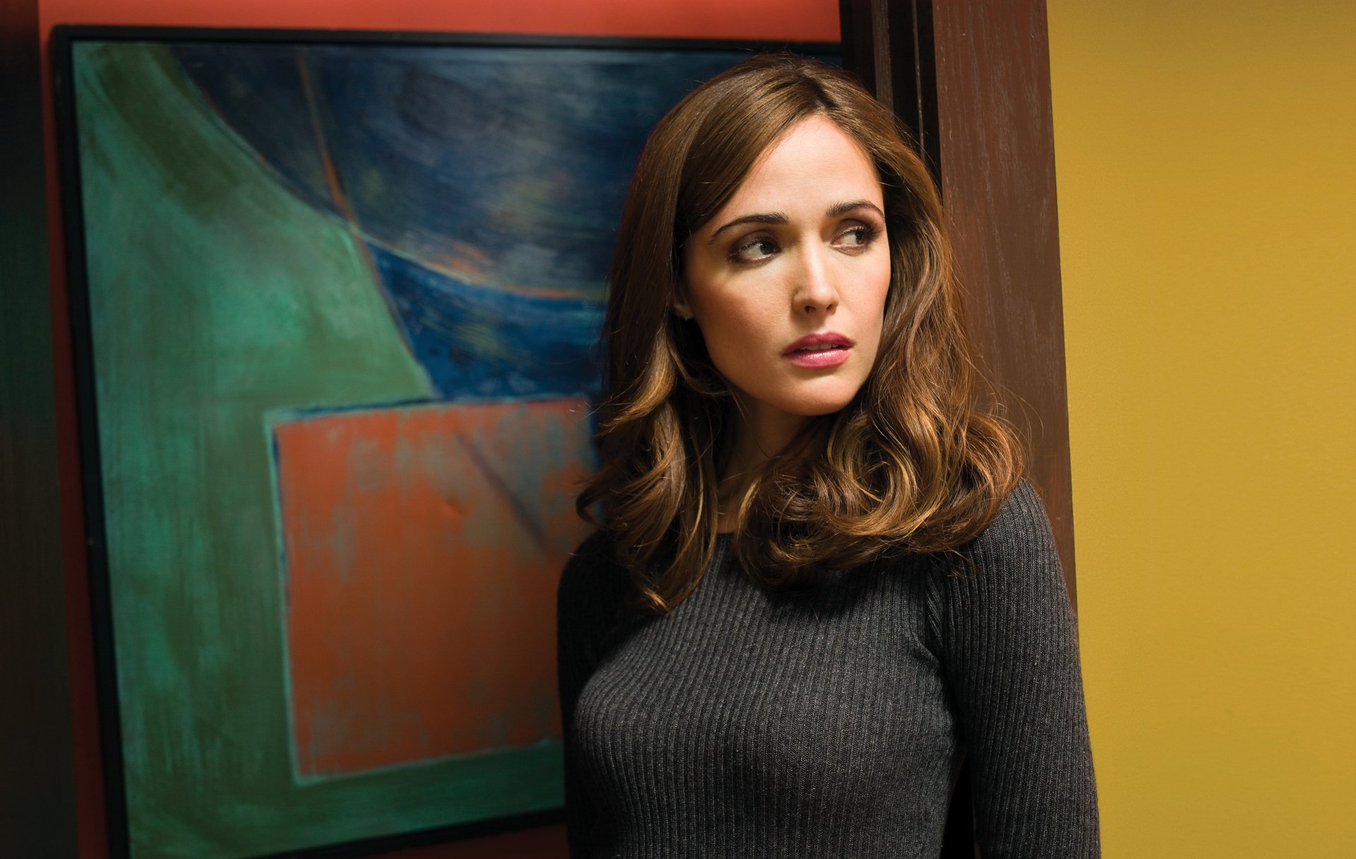 4K Ultra HD desktop wallpaper featuring celebrity Rose Byrne standing in front of a colorful abstract painting against a yellow wall.
