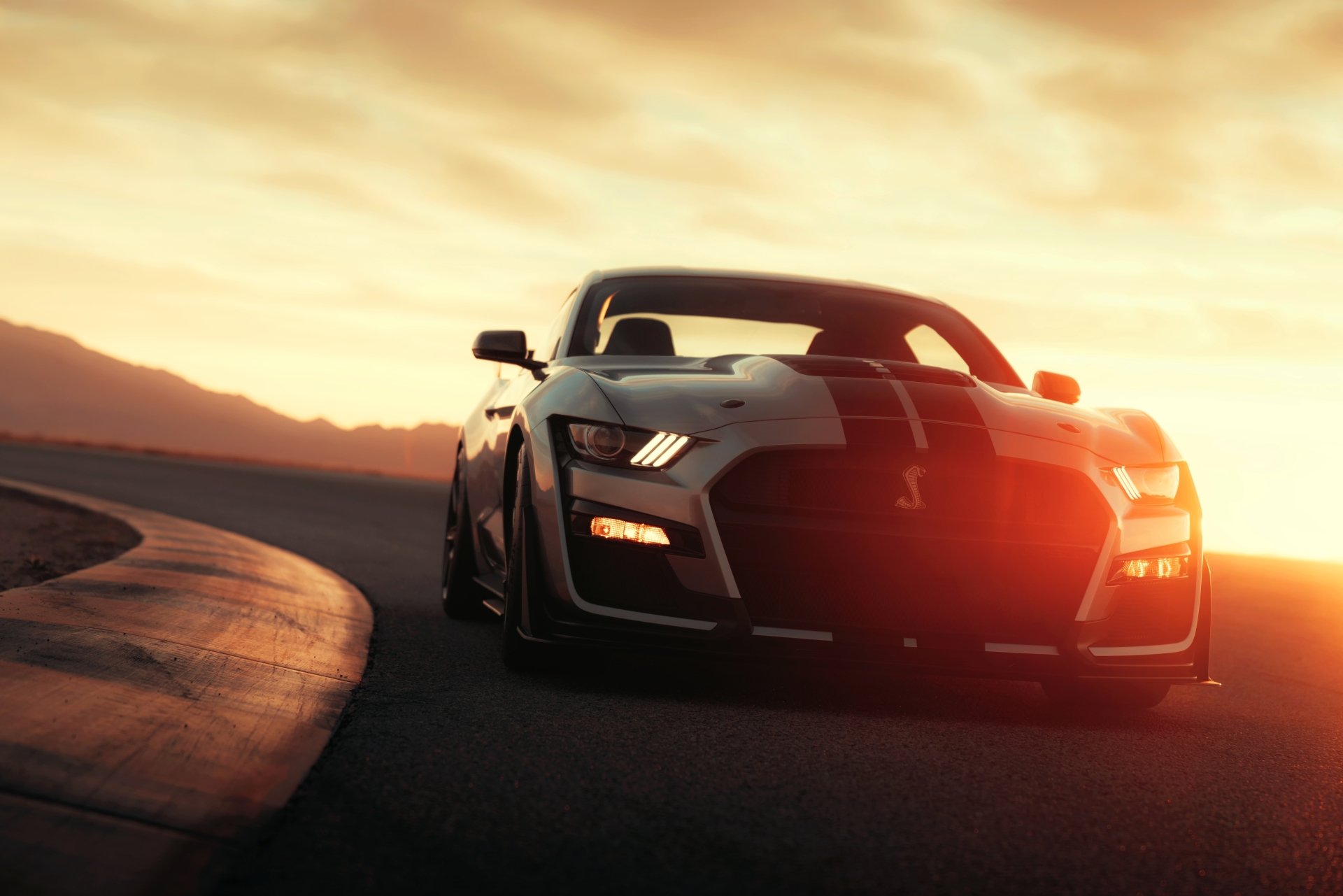 Silver Ford Mustang Shelby GT500 muscle car on a winding road at sunset, dramatic 8K Ultra HD PC desktop wallpaper