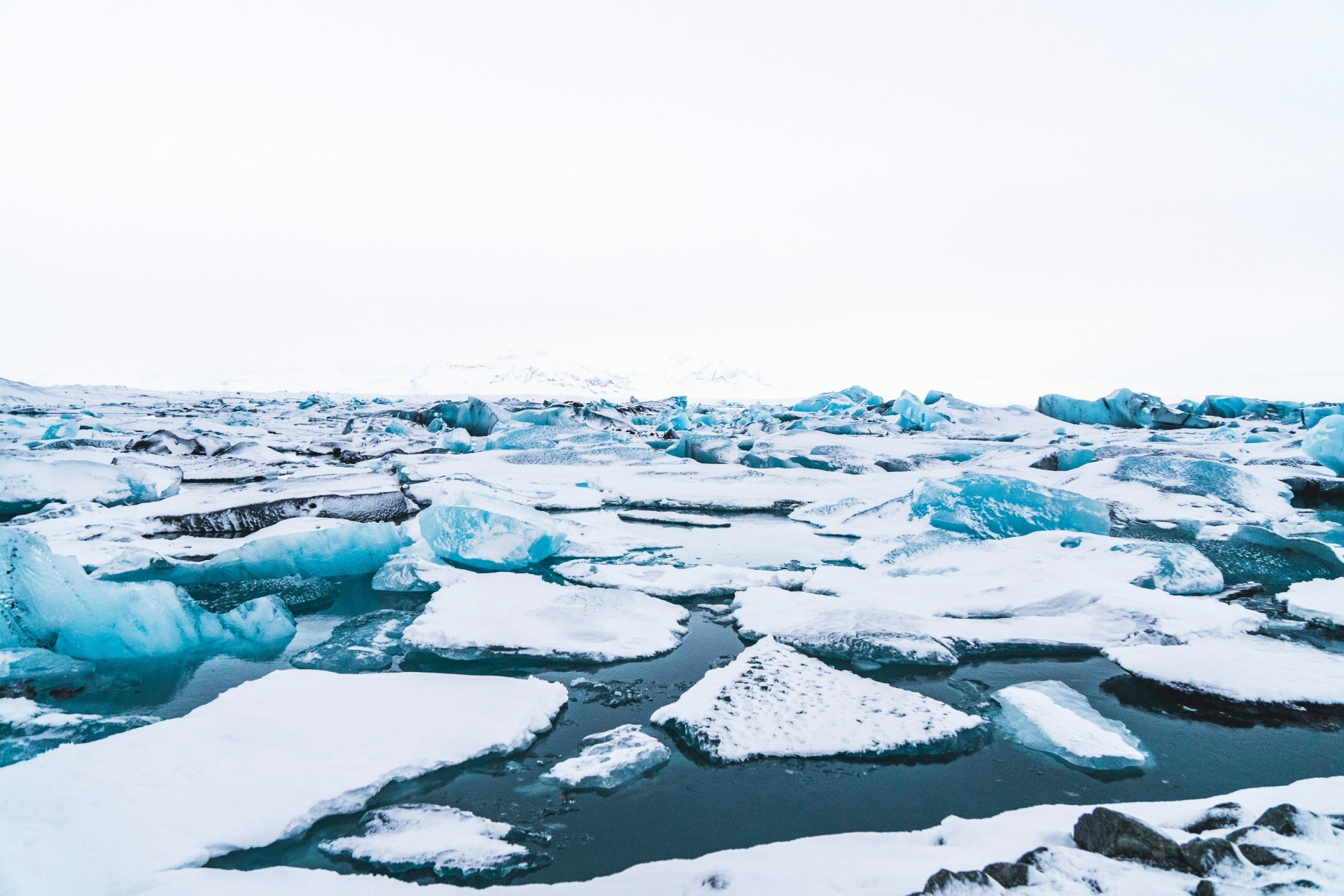 A 4K Ultra HD desktop wallpaper showcasing a serene natural scene of floating ice floes and icebergs on dark, cold water under a pale sky.