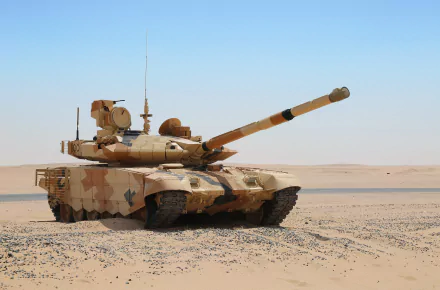 HD desktop wallpaper featuring a military T-90 tank camouflaged in desert terrain under a clear blue sky.