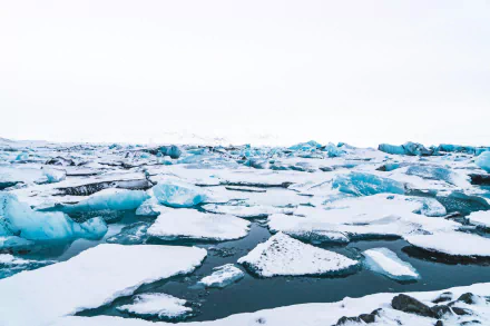 A 4K Ultra HD desktop wallpaper showcasing a serene natural scene of floating ice floes and icebergs on dark, cold water under a pale sky.