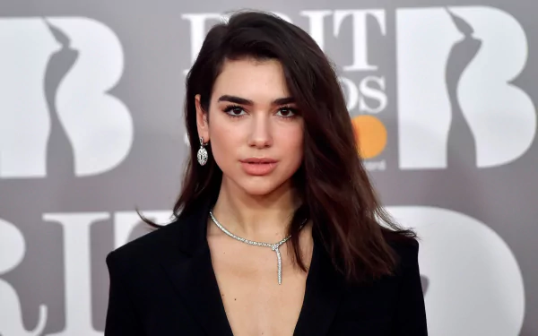 HD desktop wallpaper featuring English singer Dua Lipa with brunette hair and brown eyes, dressed elegantly at a music awards event.