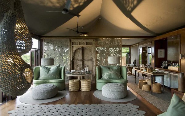 HD PC desktop wallpaper showcasing a modern living room with green armchairs, woven ottomans, textured room dividers, and ambient lighting in a stylish, man-made space.