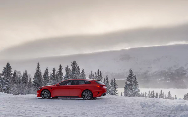 Red Kia Sportspace concept car parked on a snowy landscape with pine trees and misty mountains in the background, captured in 4K Ultra HD.