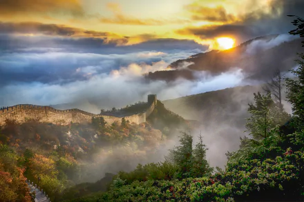 4K Ultra HD view of the Great Wall of China at sunset, with mist rolling over lush green hills under a glowing golden sky.