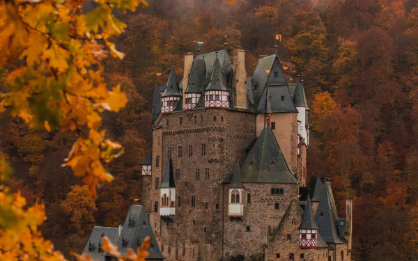 Eltz Castle, a historic man-made fortress, stands amidst autumn foliage in this HD PC desktop wallpaper and background.