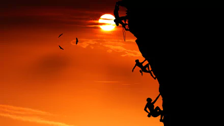 Silhouettes of climbers scaling a steep cliff against a vibrant sunset sky, with birds flying nearby, captured in stunning 4K Ultra HD.
