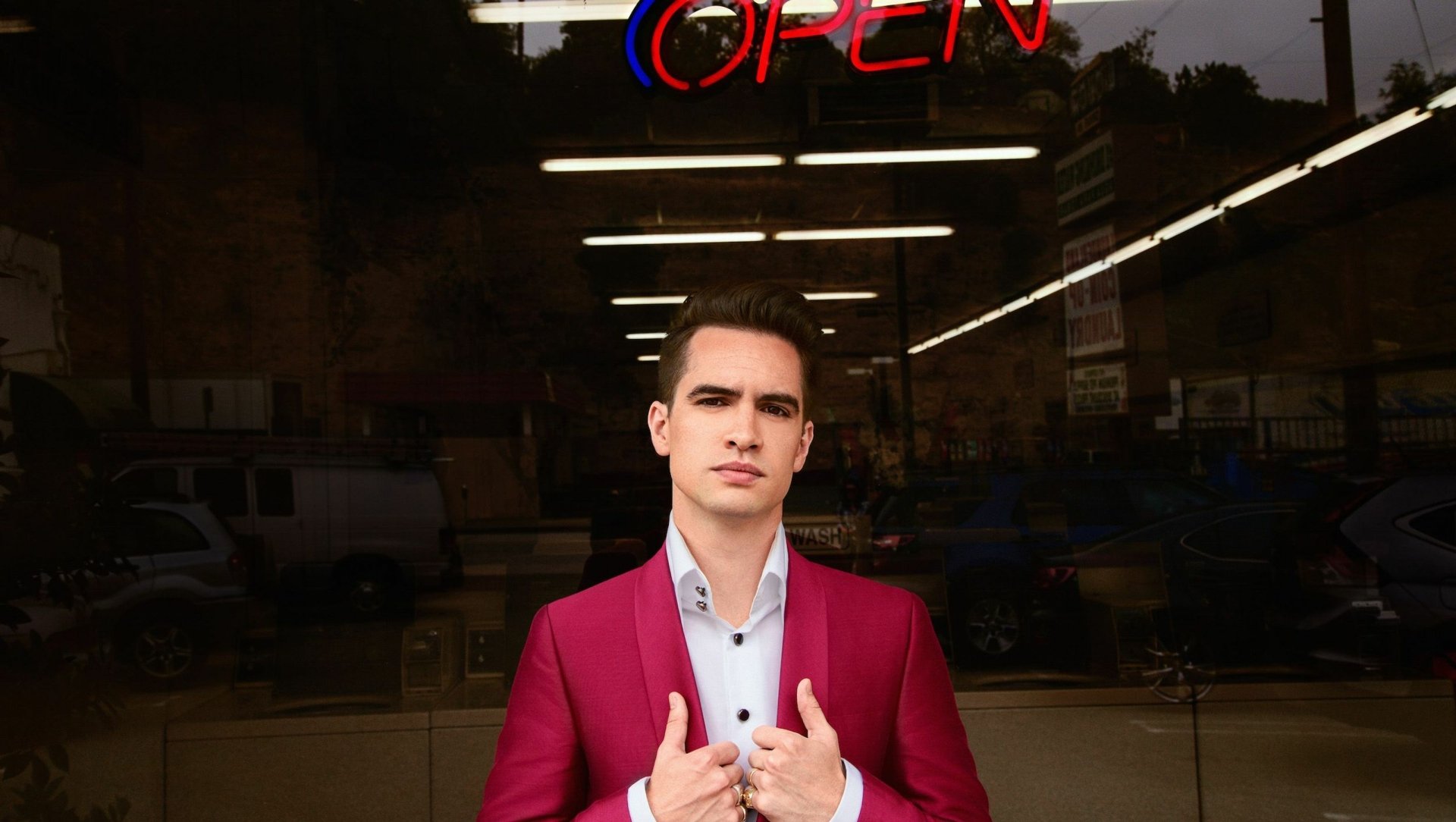 HD desktop wallpaper featuring a member of Panic! at the Disco standing before a neon OPEN sign, exuding a cool vibe.