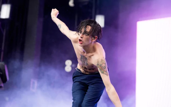 HD desktop wallpaper of a The 1975 band member performing on stage, animated and shirtless against a purple haze.